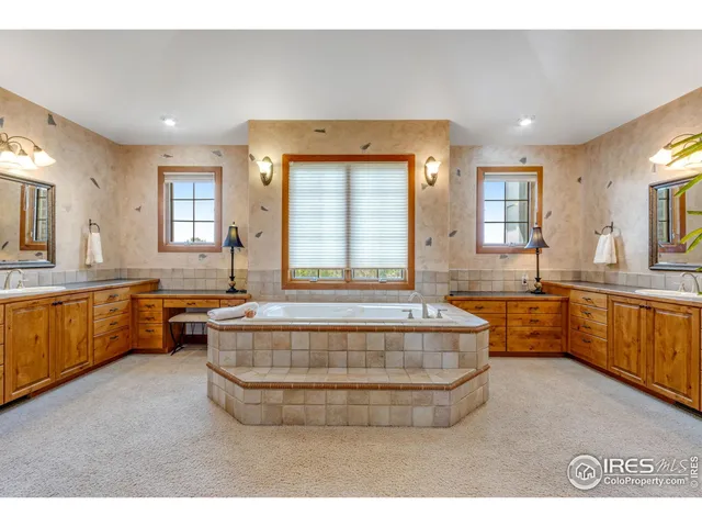 a spacious bathroom with a tub double vanity sink a mirror and a bathtub
