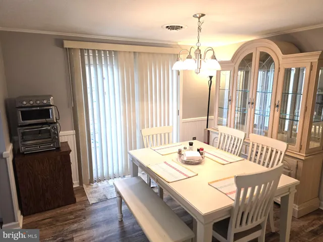 a dining room with furniture window wooden floor and a kitchen view
