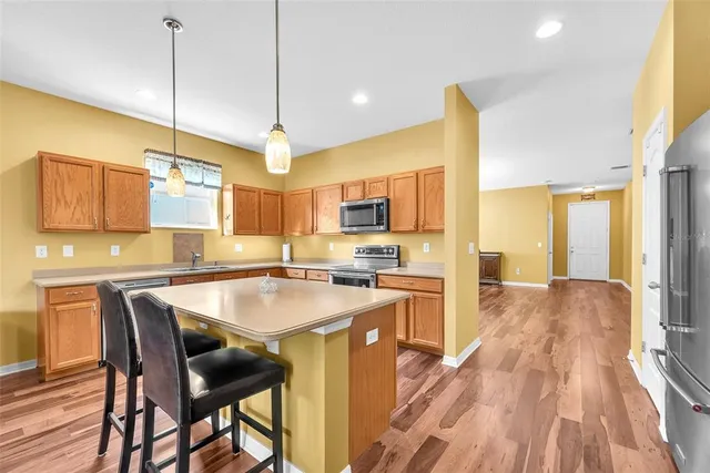 a kitchen with stainless steel appliances granite countertop a sink a stove a refrigerator a microwave oven with cabinets and wooden floor