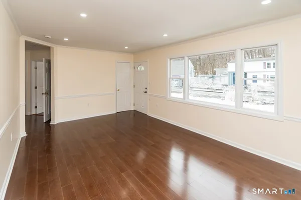 a view of an empty room with wooden floor and a window