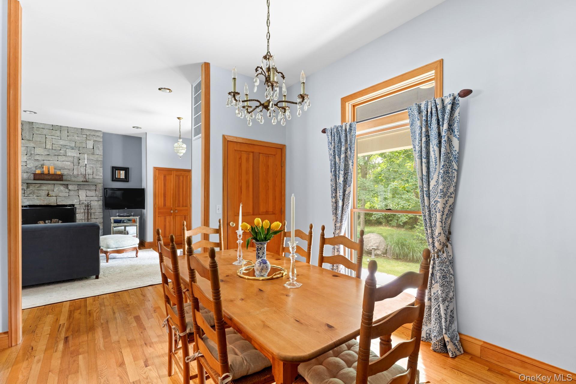 2 Sunset Road Sag Harbor, NY 11963 - Photo 7 of 21 Dining space featuring light wood-style flooring, a chandelier, and a stone fireplace
