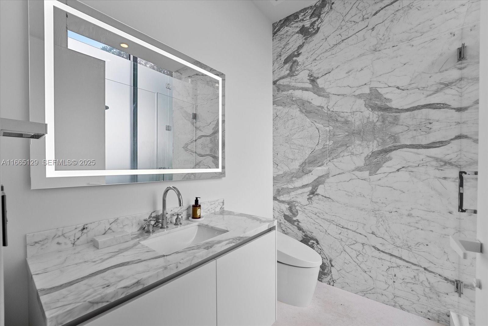 2811 South Bayshore Drive, Unit 4C Miami, FL 33133 - Photo 28 of 37 a bathroom with a granite countertop sink a toilet and a mirror