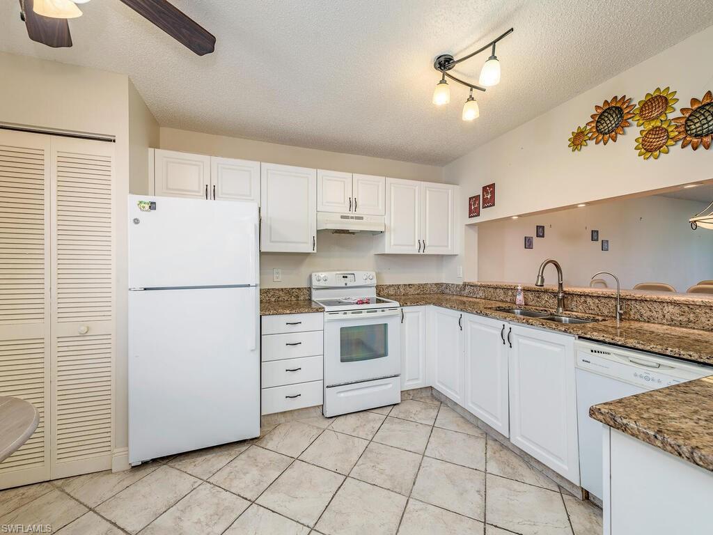 5920 Cranbrook Way, Unit F106 Naples, FL 34112 - Photo 6 of 12 a kitchen with granite countertop cabinets and white appliances