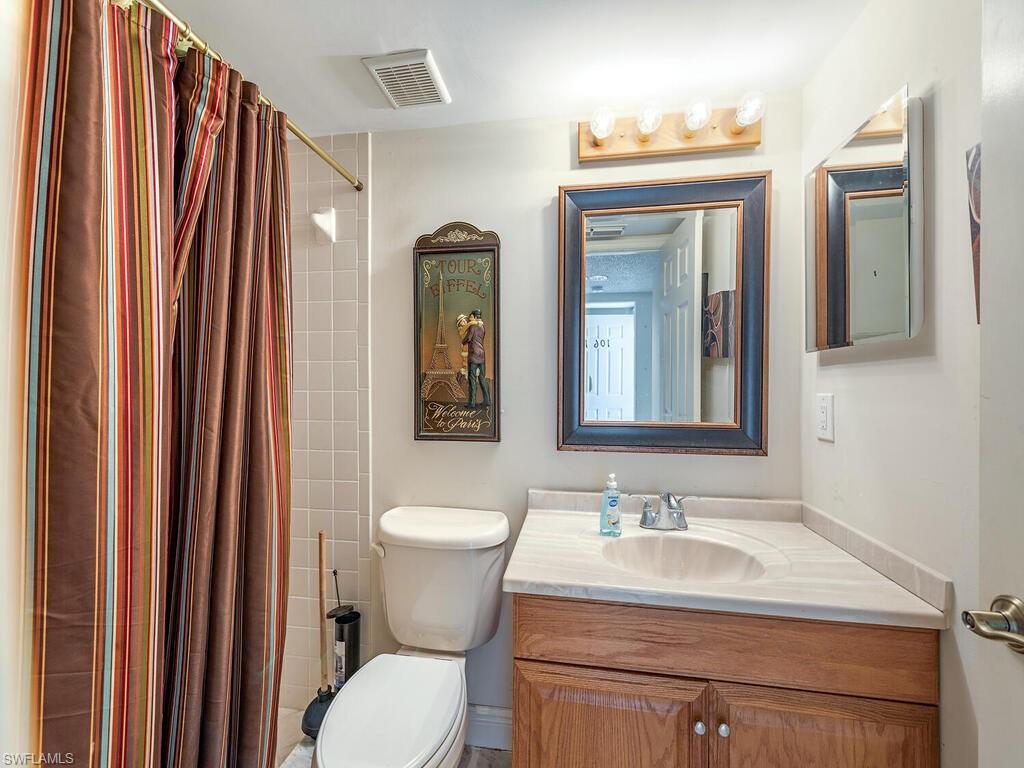 5920 Cranbrook Way, Unit F106 Naples, FL 34112 - Photo 10 of 12 a bathroom with a granite countertop sink toilet and mirror