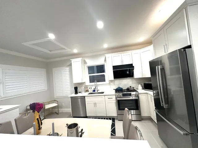 a kitchen with stainless steel appliances kitchen island granite countertop a sink refrigerator and microwave