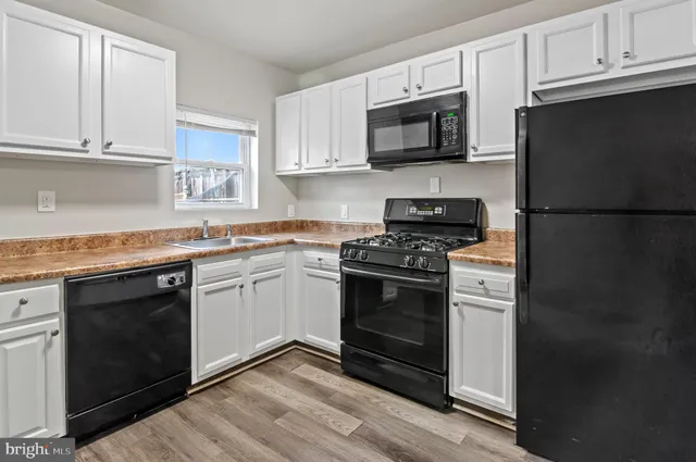 a kitchen with cabinets stainless steel appliances and wooden floor