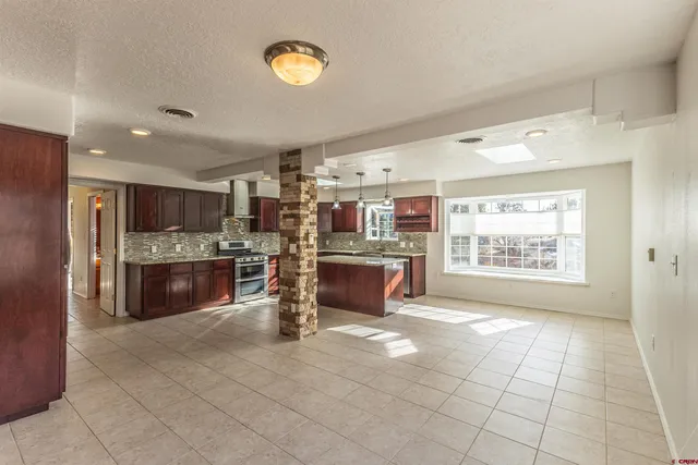 a large kitchen with stainless steel appliances granite countertop a stove a sink a microwave a counter top and cabinets