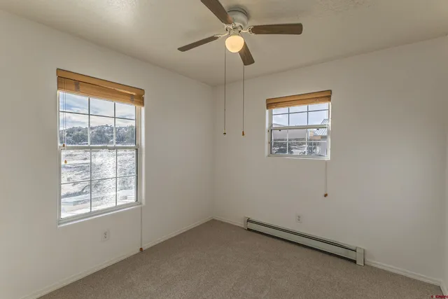 en empty room with windows and ceiling fan