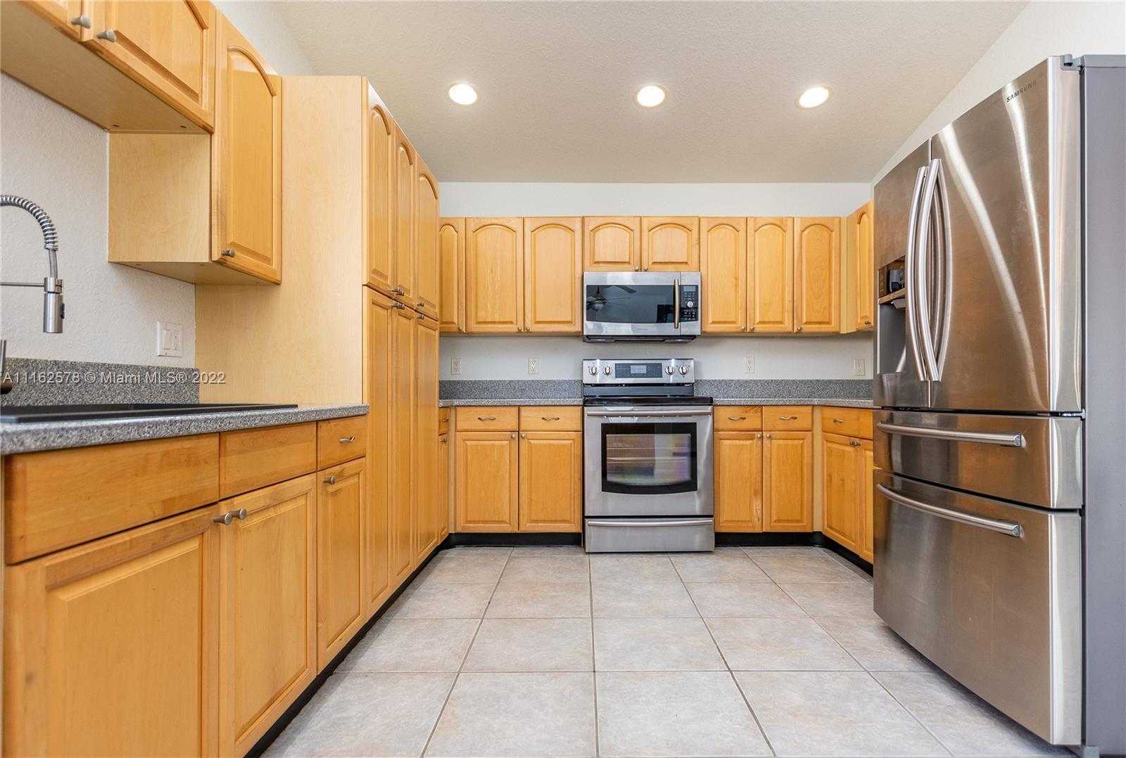 11612 Quiet Waters Lane Boca Raton, FL 33428 - Photo 27 of 70 a kitchen with stainless steel appliances granite countertop a refrigerator sink and stove