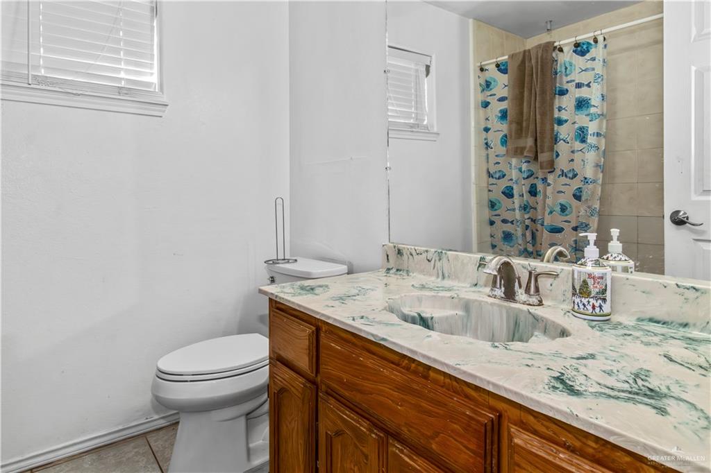 2509 Coma Street Hidalgo, TX 78557 - Photo 11 of 12 a bathroom with a granite countertop sink a toilet and a mirror