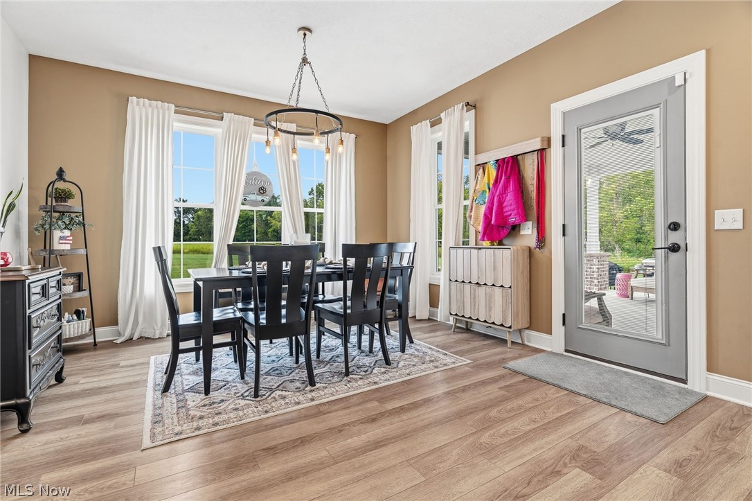 421 Pontius Road Mogadore, OH 44260 - Photo 6 of 50 Wood-finish flooring, multiple large windows with white trim, a modern chandelier, and a glass-paneled exterior door
