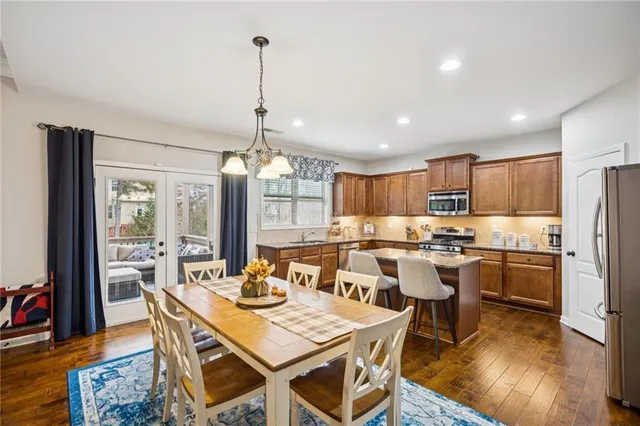 a kitchen with granite countertop kitchen island stainless steel appliances a stove a sink a refrigerator cabinets and dining table