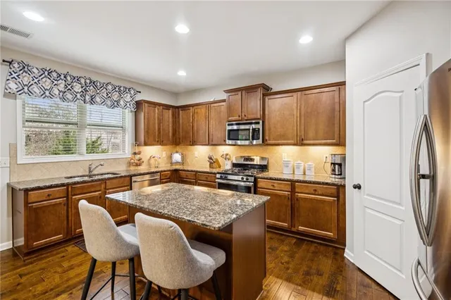 a kitchen with stainless steel appliances granite countertop a table chairs and a refrigerator