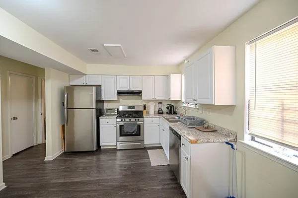 a kitchen with a refrigerator a stove a sink and white cabinets