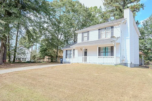 a front view of a house with a garden and trees