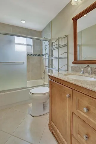 a bathroom with a granite countertop sink toilet a mirror and shower