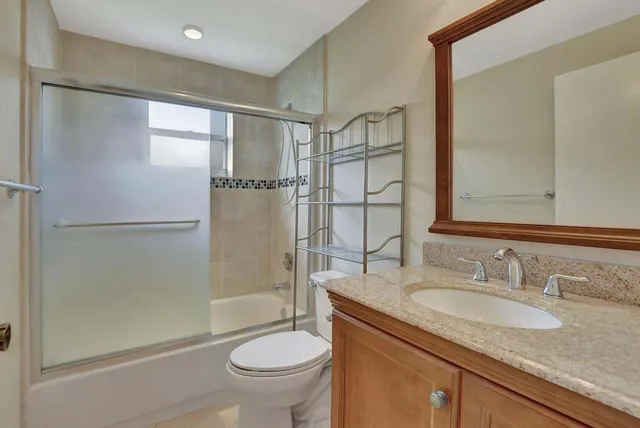a bathroom with a granite countertop sink toilet and shower