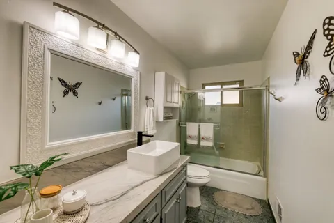 a bathroom with a granite countertop sink toilet a mirror and shower