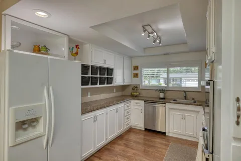 a kitchen with stainless steel appliances granite countertop a sink and dishwasher with white cabinets
