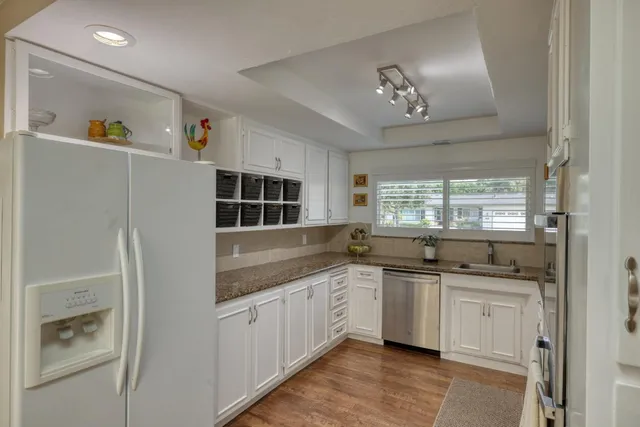 a kitchen with stainless steel appliances granite countertop a sink and dishwasher with white cabinets