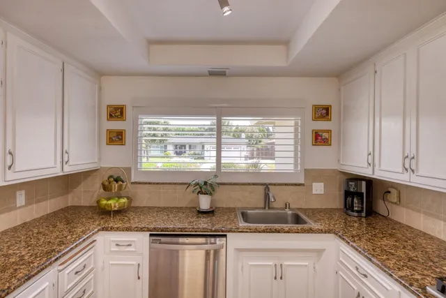a kitchen with granite countertop a sink a window and cabinets
