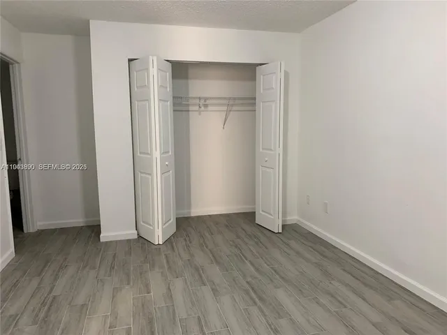an empty room with wooden floor & closet area