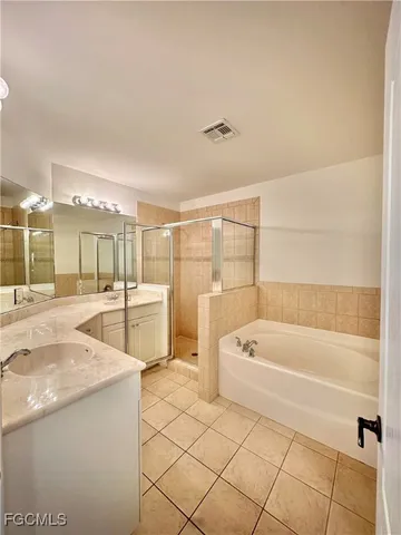 a spacious bathroom with a tub a mirror and a shower