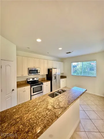 a large kitchen with stainless steel appliances kitchen island granite countertop a sink and cabinets