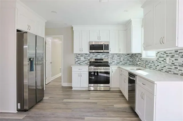 a kitchen with stainless steel appliances granite countertop white cabinets granite counter tops and a wooden floors