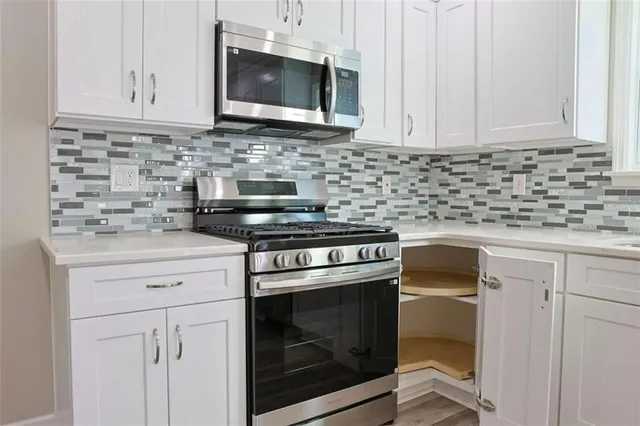 a kitchen with stainless steel appliances granite countertop white cabinets granite counter tops and a wooden floors