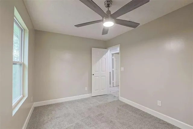 an empty room with a window and a fan