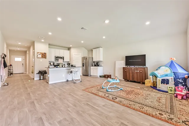 a view of kitchen with kitchen island microwave stove refrigerator and couches with wooden floor