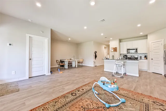 a living room with furniture and kitchen view with wooden floor