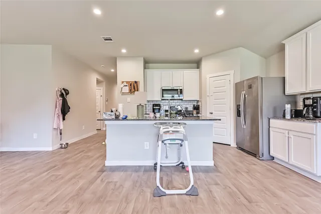 a kitchen with kitchen island white cabinets and stainless steel appliances