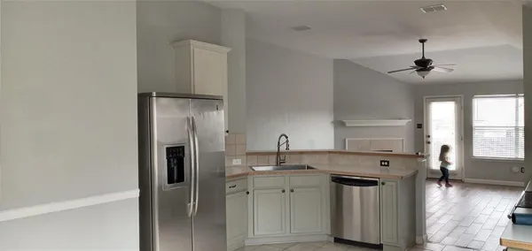 a view of a kitchen with a sink and dishwasher a refrigerator with wooden floor
