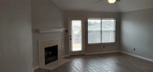 an empty room with wooden floor fireplace and windows
