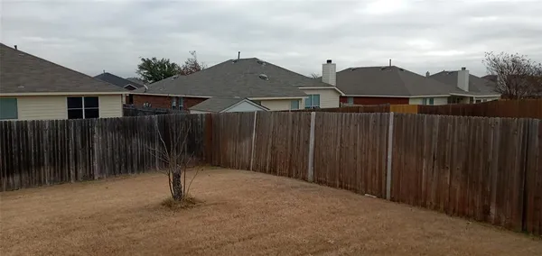 a backyard of a house with lawn chairs and wooden fence