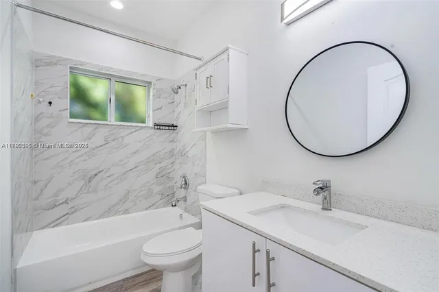 a bathroom with a sink a mirror a toilet and a bathtub