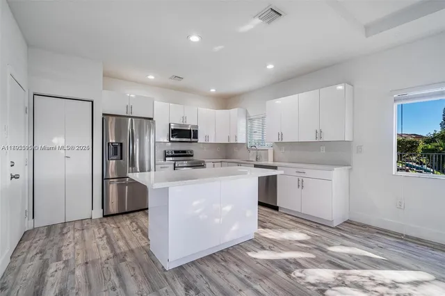 a kitchen with refrigerator a microwave and white cabinets