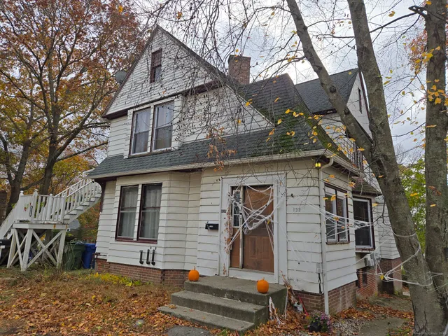 a front view of a house with a tree