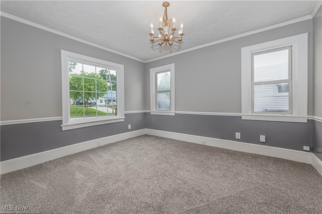 197 East Wilbeth Road Akron, OH 44301 - Photo 8 of 22 Unfurnished Dining room with ornamental molding, a chandelier, carpet, and baseboards