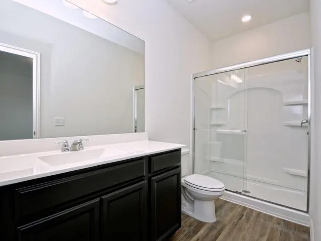a bathroom with a granite countertop sink toilet a mirror and shower