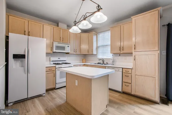 a kitchen with a refrigerator a sink and dishwasher with white cabinets