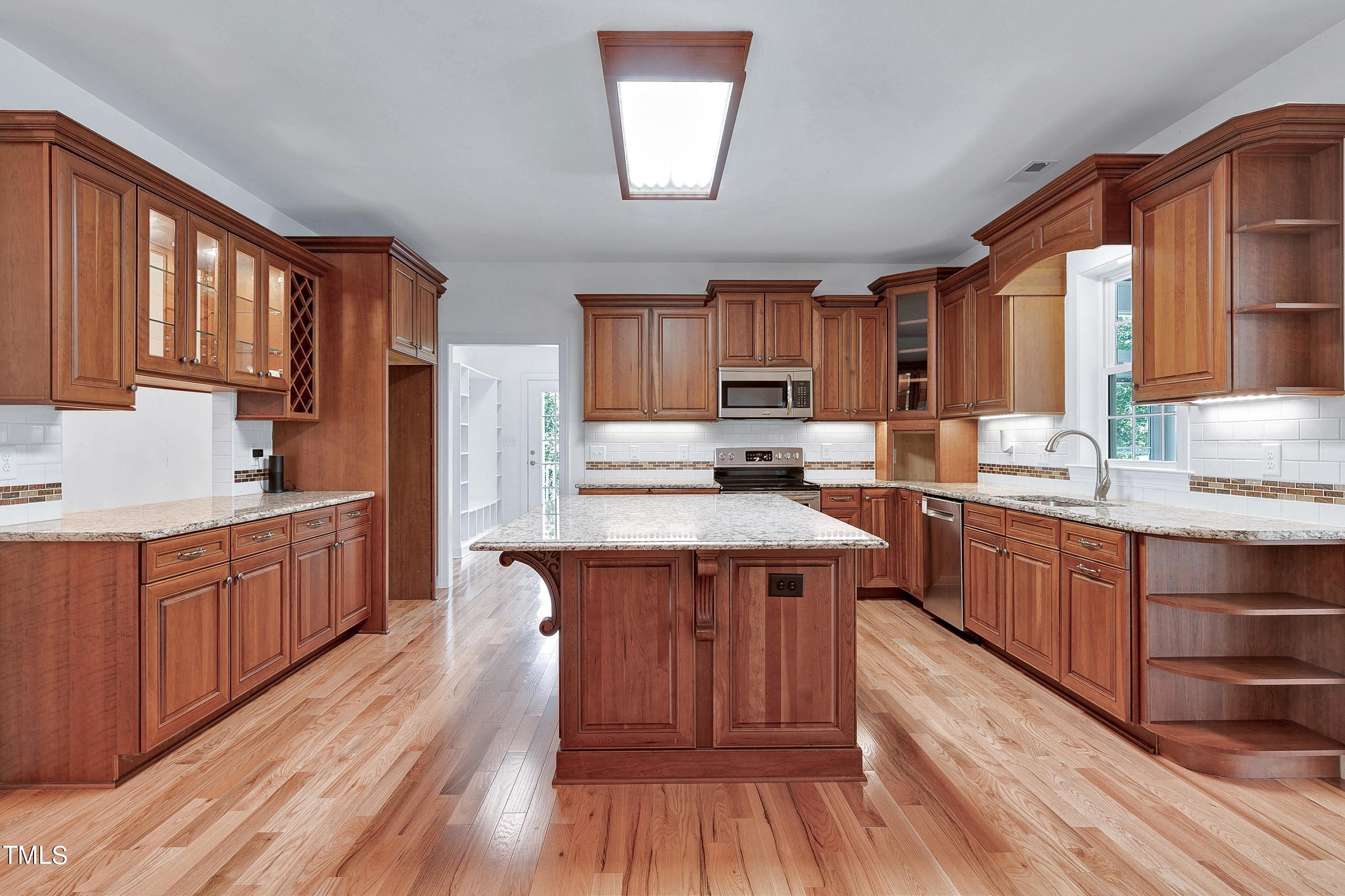 644 Uwharrie Ridge Road Chapel Hill, NC 27516 - Photo 16 of 43 a kitchen with stainless steel appliances granite countertop wooden floors wooden cabinets and sink