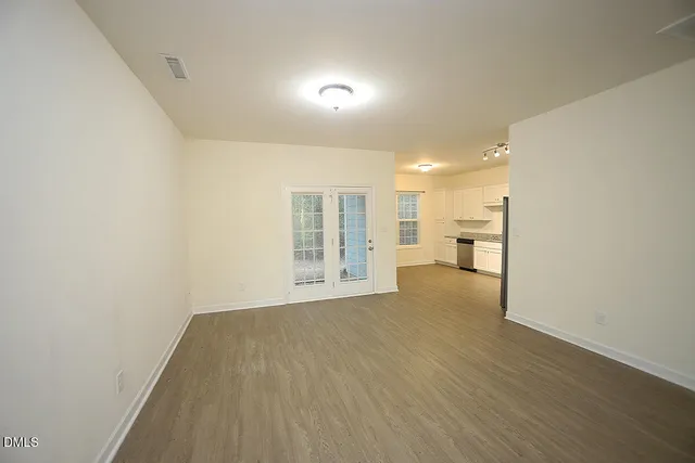 a view of an empty room with wooden floor and a window