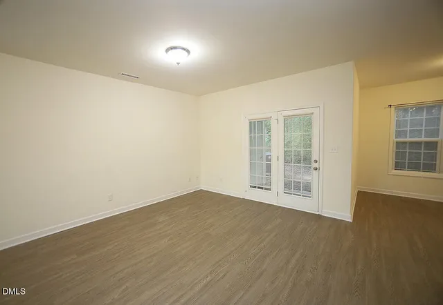 a view of an empty room with wooden floor and windows