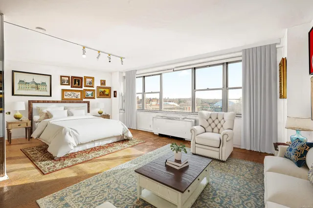 a spacious bedroom with a bed a couch and a large window