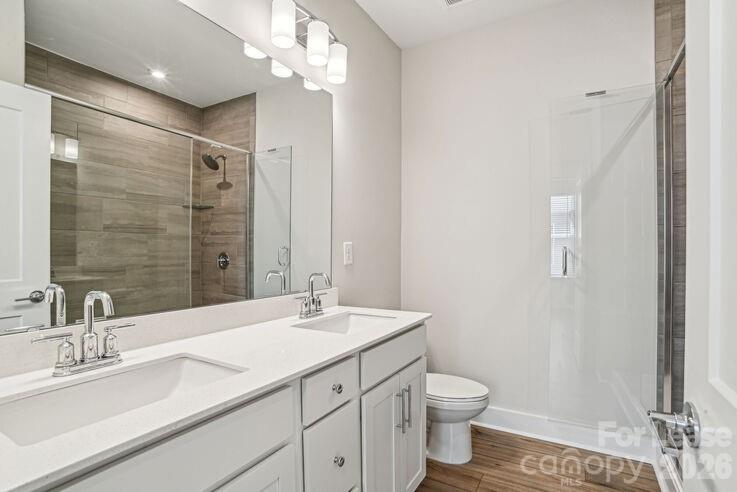 4375 Raleigh Street, Unit C1 Charlotte, NC 28213 - Photo 14 of 19 a bathroom with a double vanity sink a toilet and a mirror