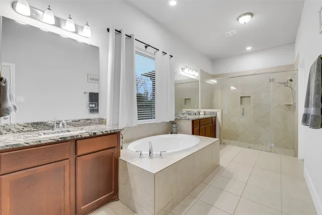 a bathroom with a granite countertop sink a mirror a bathtub and shower