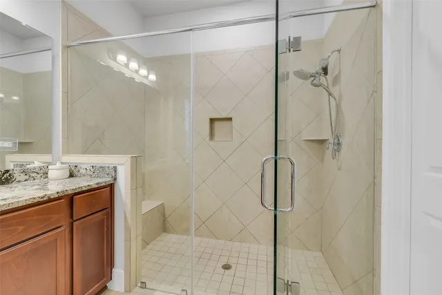 a bathroom with a granite countertop shower a sink and mirror